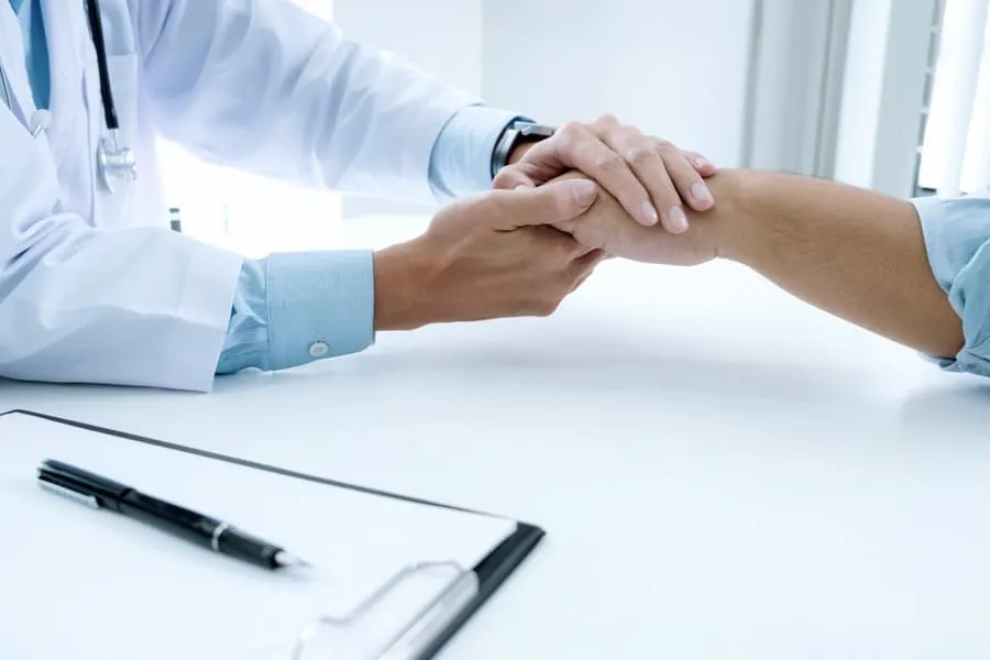 A doctor shaking hands with a patient during a consultation